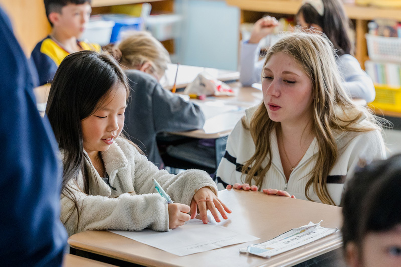 people read books to seated children in a classroom.