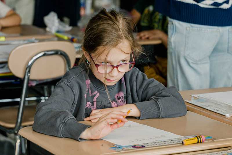 people read books to seated children in a classroom.