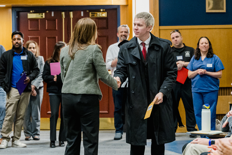 A diverse group of professionals, dressed in business attire, stand on stage