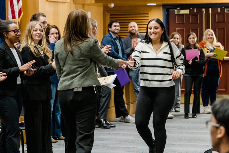 A diverse group of professionals, dressed in business attire, stand on stage