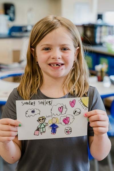 Student proudly holding artwork.