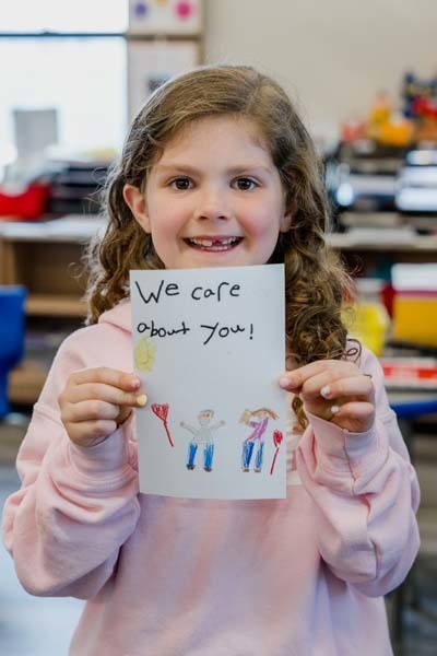 Student proudly holding artwork.