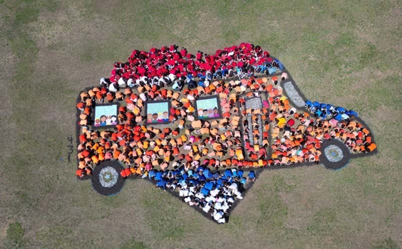 Aerial view of students making a bus on the field.