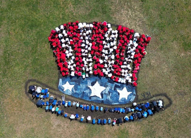 Aerial view of students making a USA colored hat on the field.