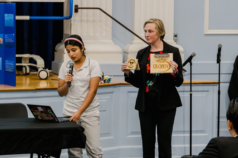 Educator addressing an audience at a school event with a focus on community engagement and learning.
