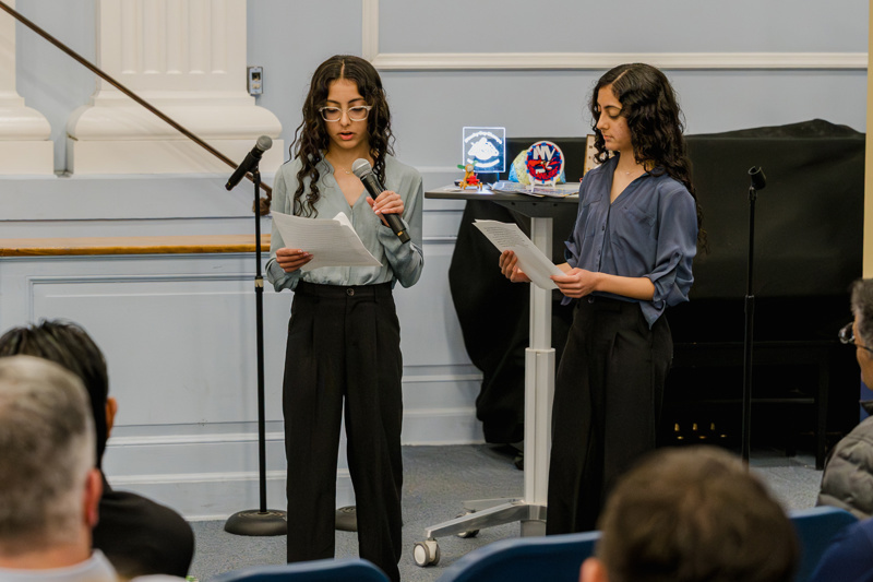 Educator addressing an audience at a school event with a focus on community engagement and learning.