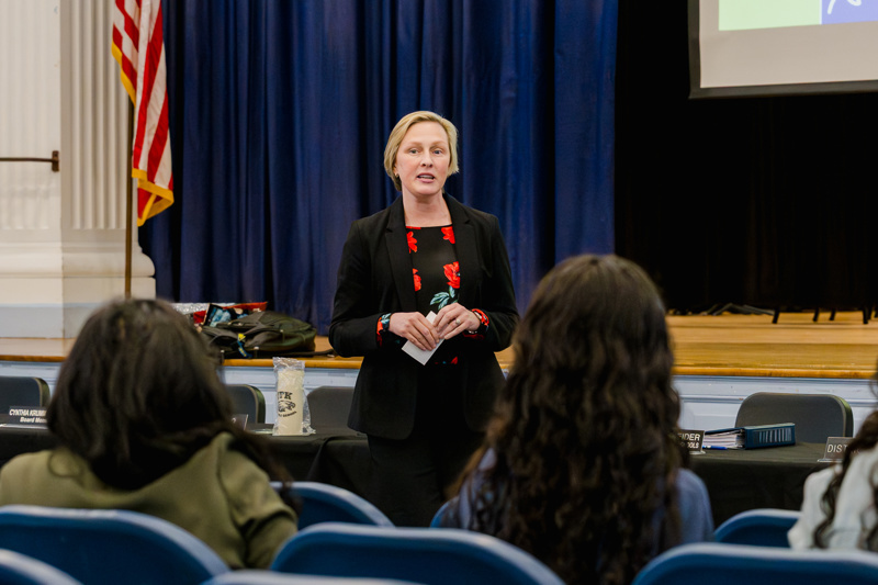 Educator addressing an audience at a school event with a focus on community engagement and learning.