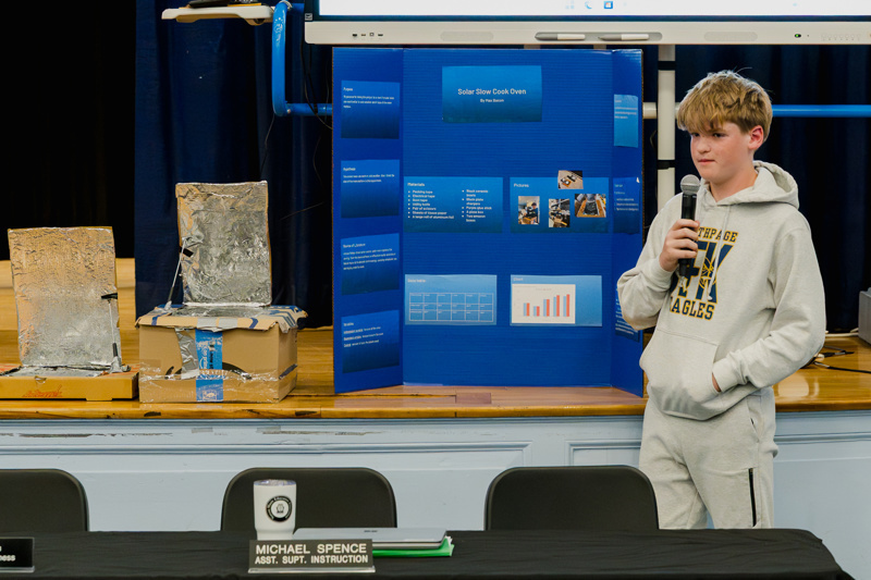 Educator addressing an audience at a school event with a focus on community engagement and learning.