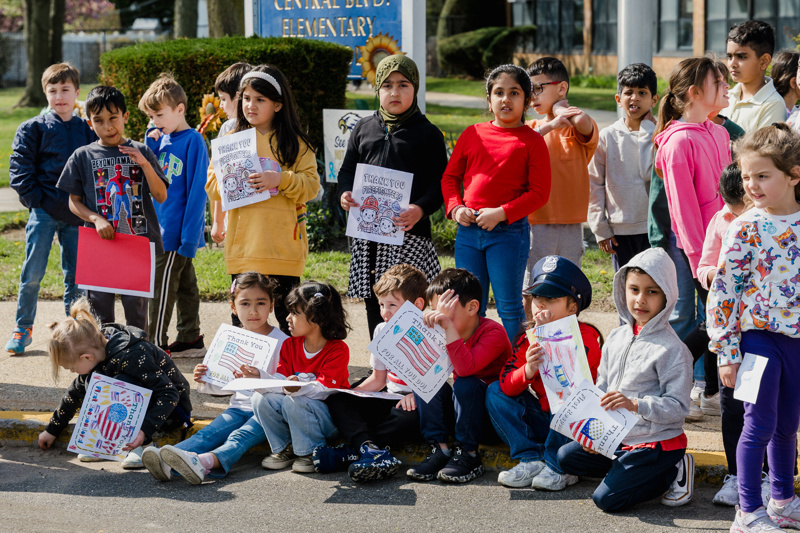 Community event at Central Boulevard Elementary with children and firefighters enjoying a meal together, fostering relationships and celebration.