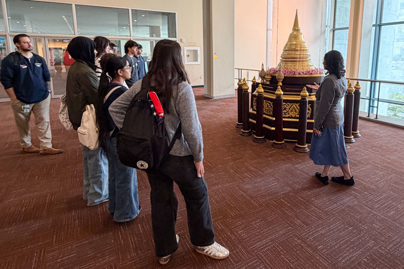 Group of visitors observing a traditional decorative structure during a museum tour, highlighting cultural appreciation and engagement.