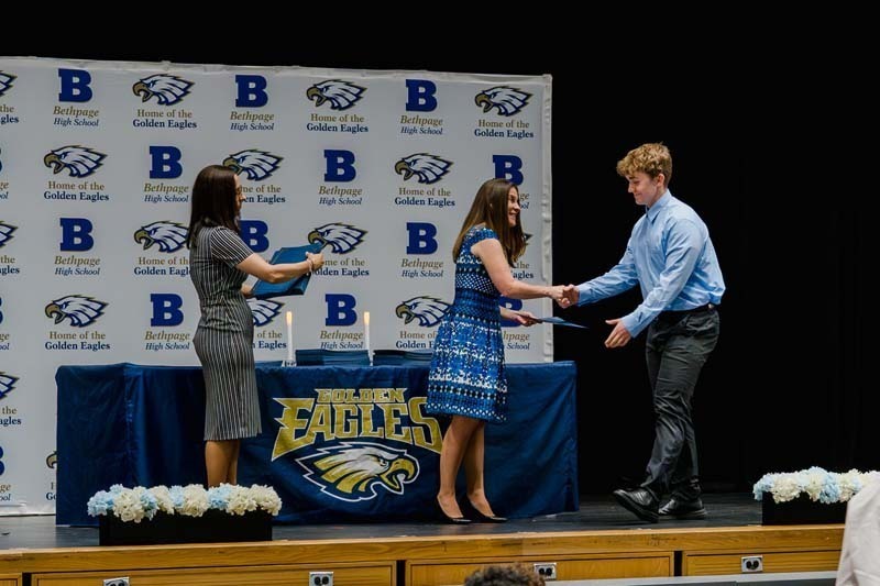Student shaking hand with administrators.
