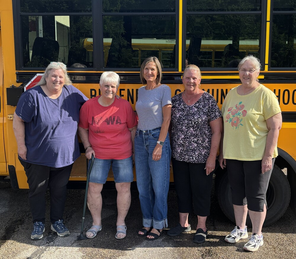 Marsha Baker, Linda Burress, Jen DeSha, Karen Farnum, and Tina Dau standing in front of a school bus.