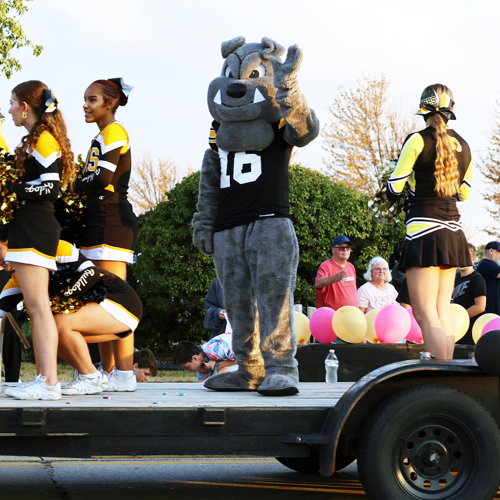 Bobby bulldog waves from a float with BHS cheerleaders