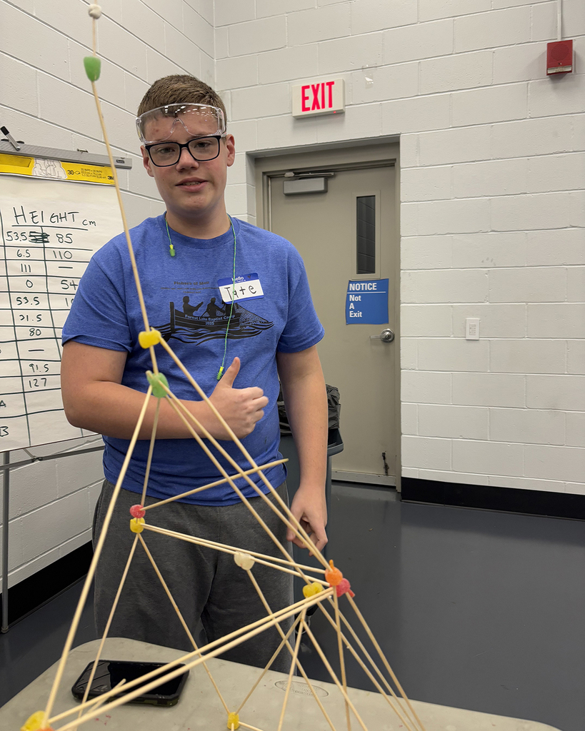 Tate posing by the structure he built with skewers and gum drops
