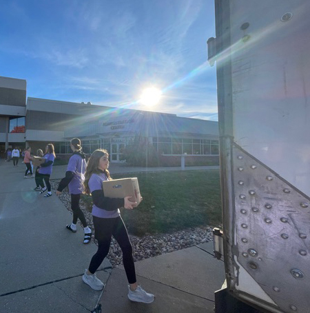 Students loading boxes with the sun in the background