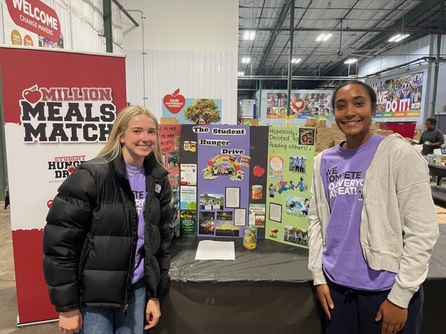 Students at River Bend Food Bank in front of a hunger drive display