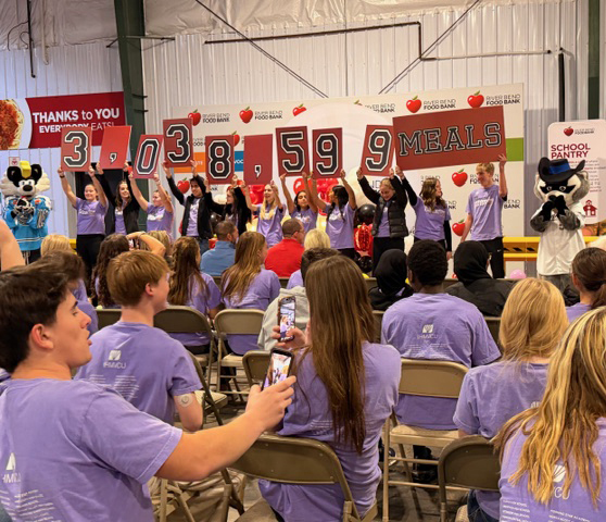 Students holding up cards reading "3,038,599 Meals" donated