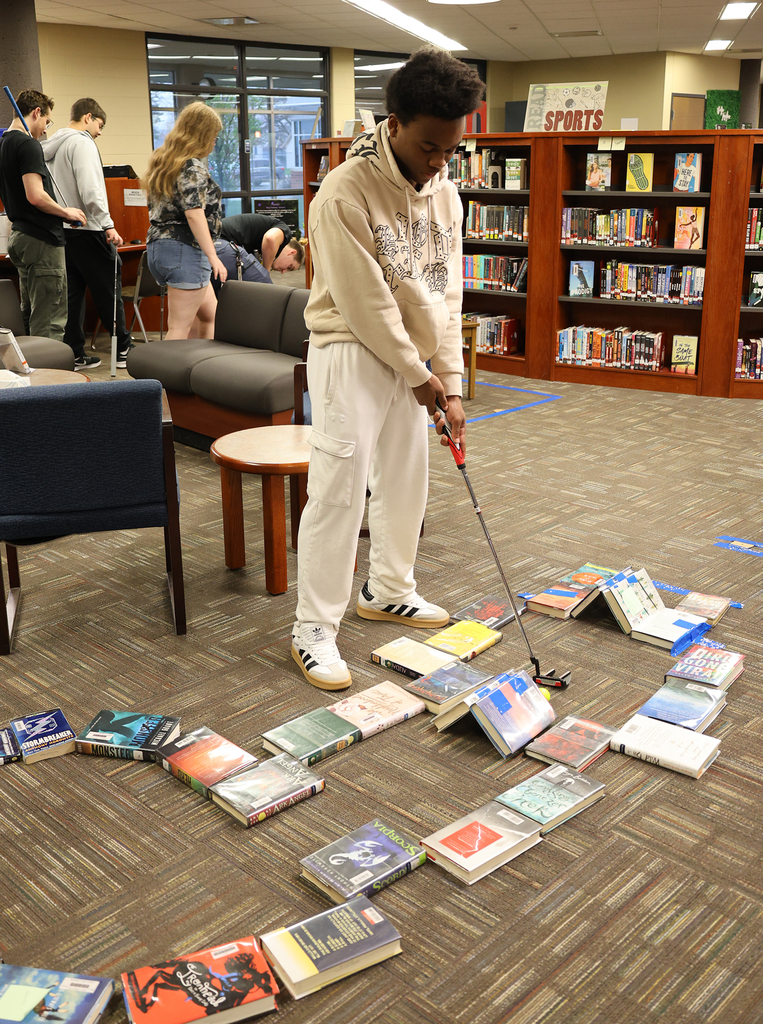 Library Mini Golf - Student working through a golf maze of books