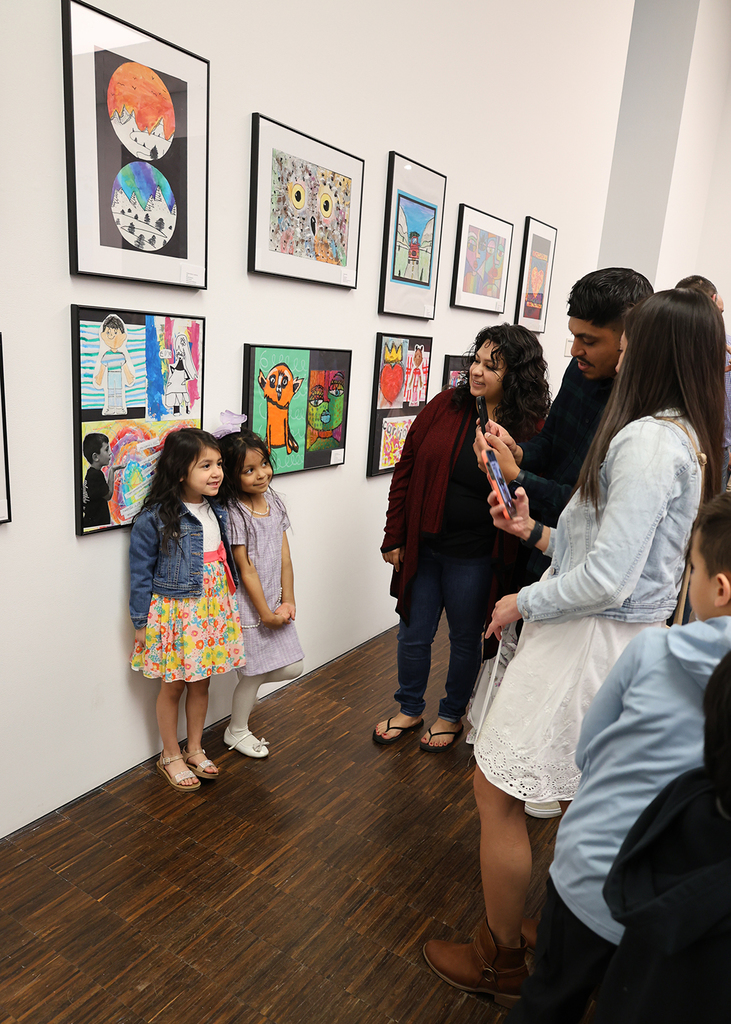 Elementary art showcase at The Figge - two girls pose in front of their art for a family taking pics