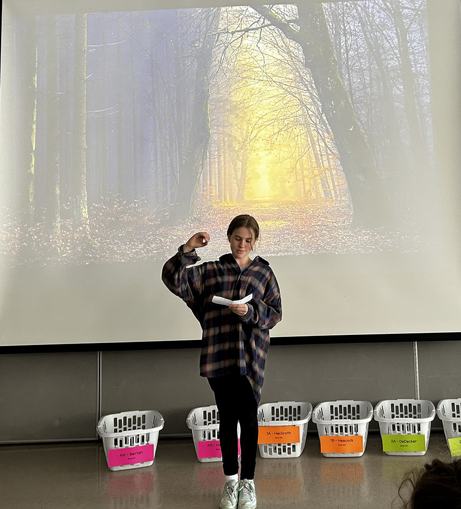 Student  speaking in front of  a sunlit path through the woods