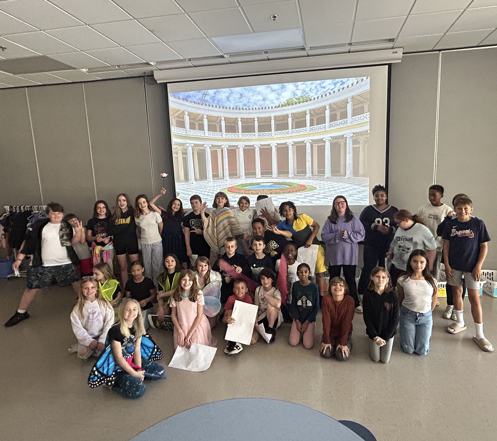 A large group of the cast pose for a picture  in front of the royal court