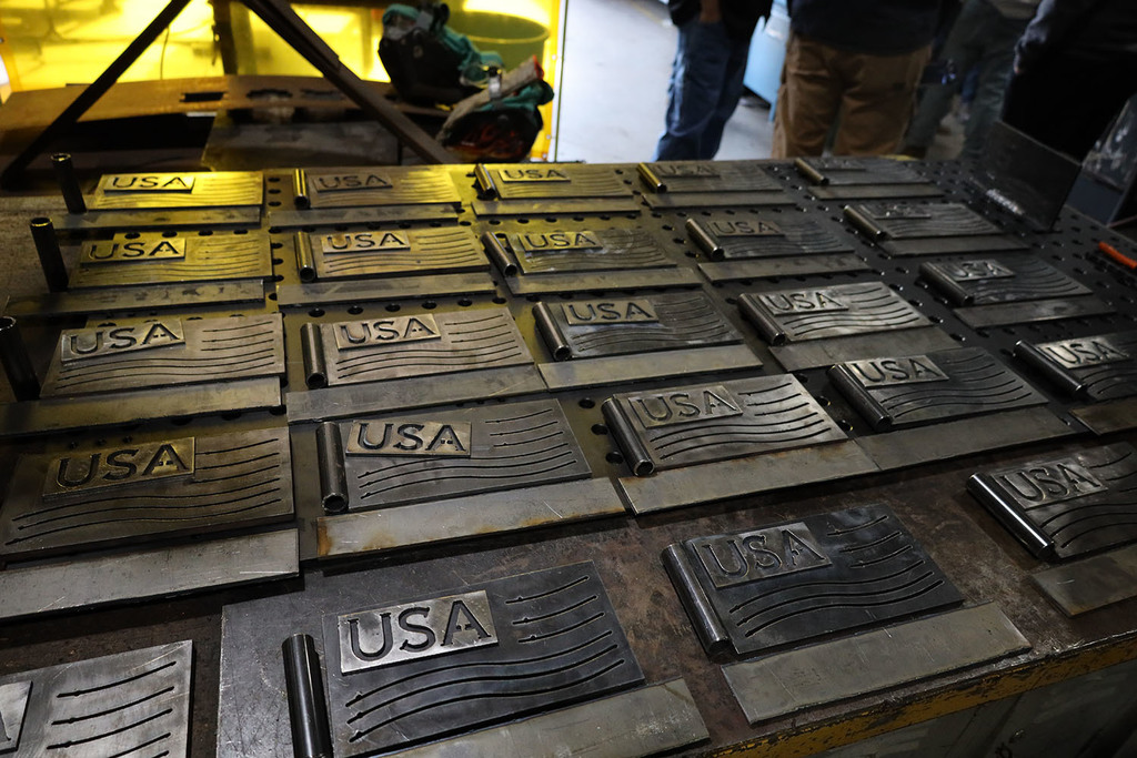 A close up of a tale of the  metal plates with USA cut into it and wavey lines like a flag next to it an below