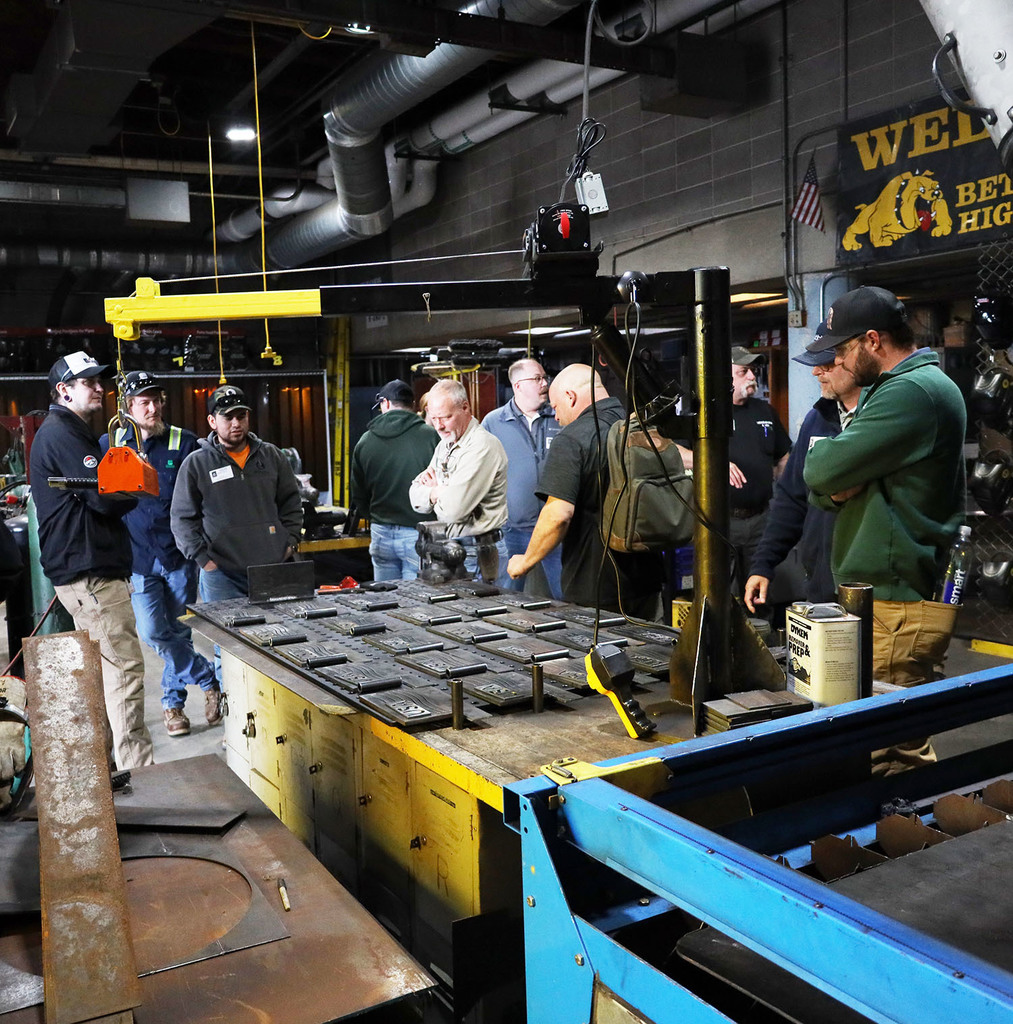 Adults looking at the metal plates with USA cut into it and wavey lines like a flag next to it an below
