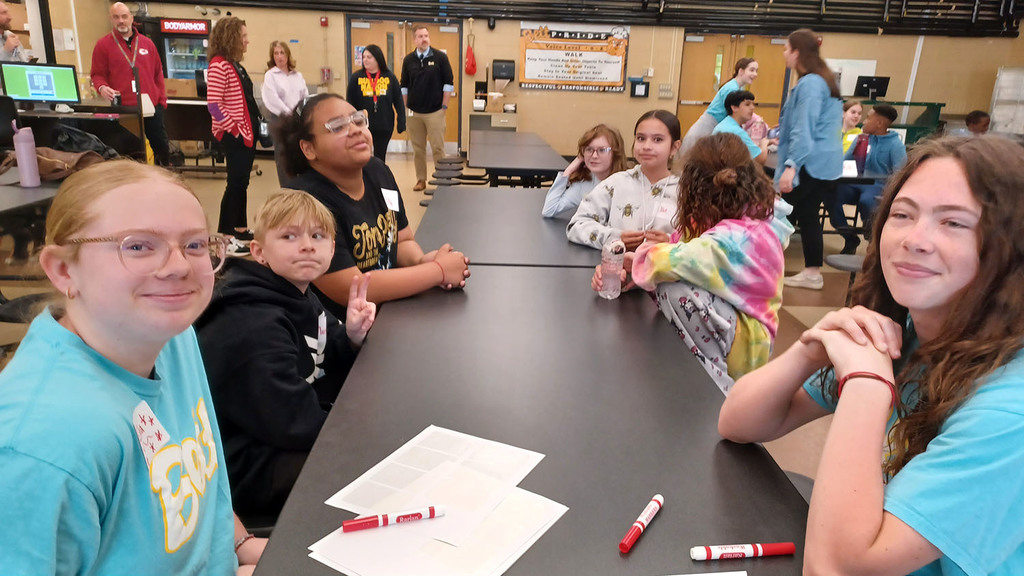 Middle school girls visiting with 5th grade student in the cafeteria