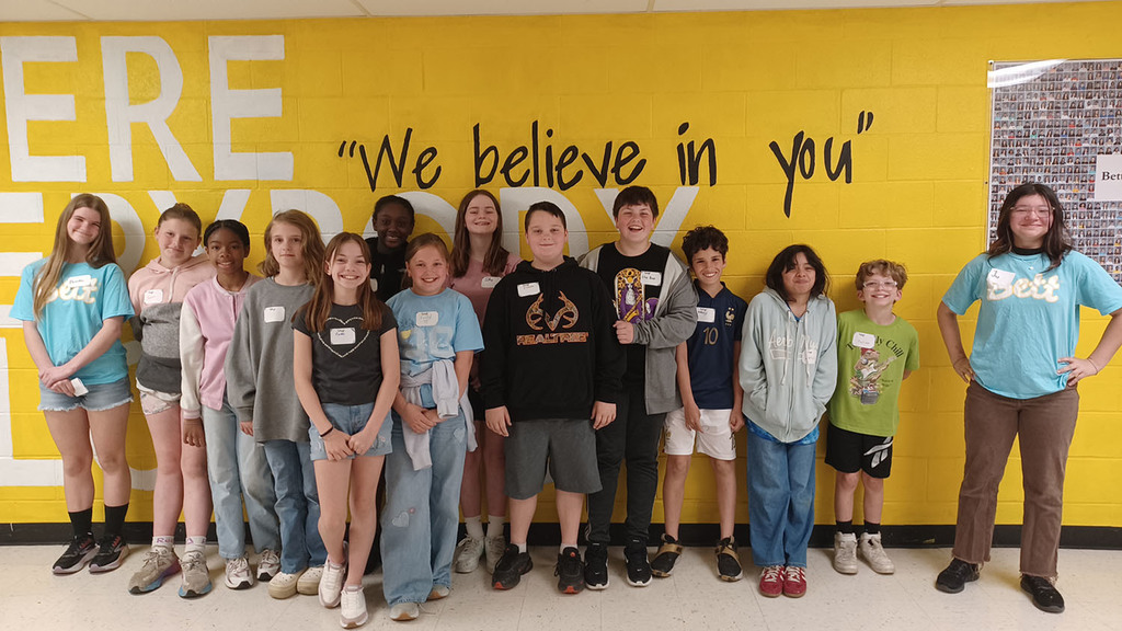 A group of 5th grade students in front of the "Where Everybody Belongs" wall