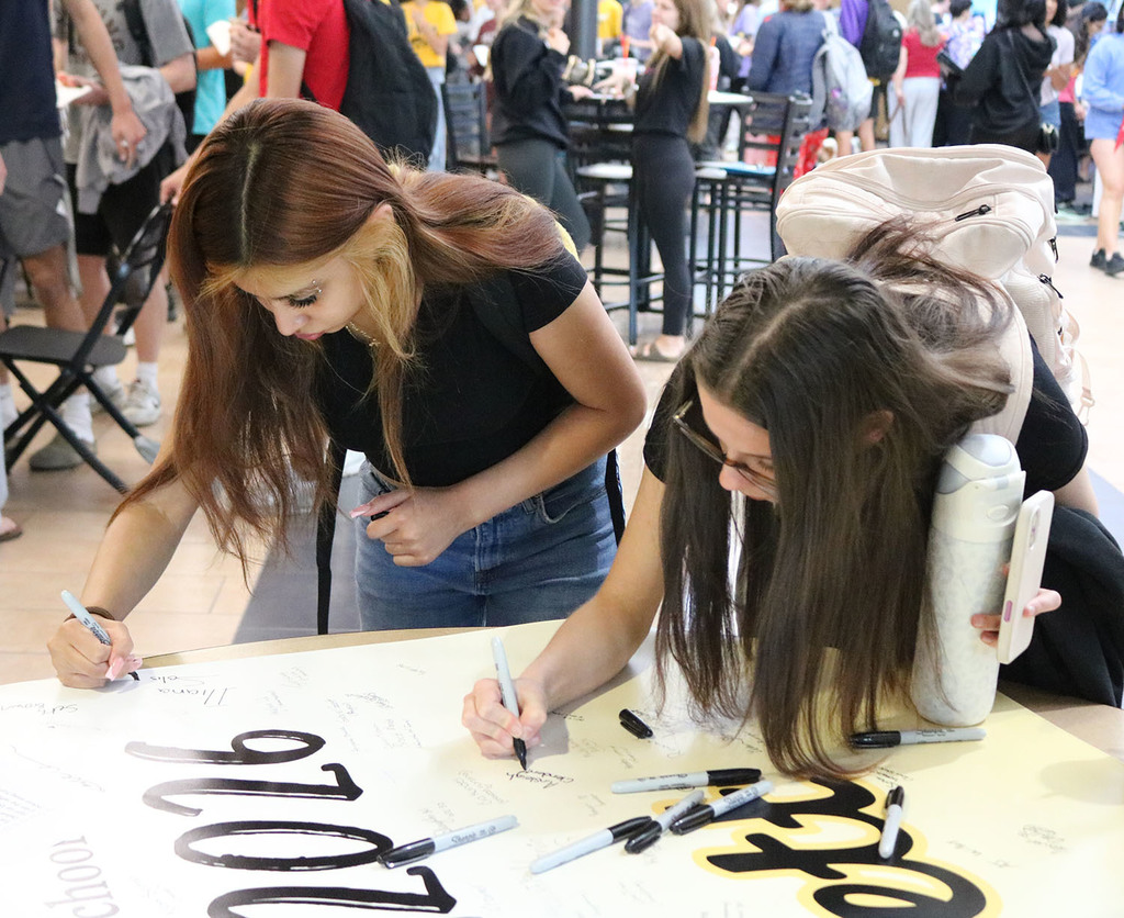 Girls signing the class poster.
