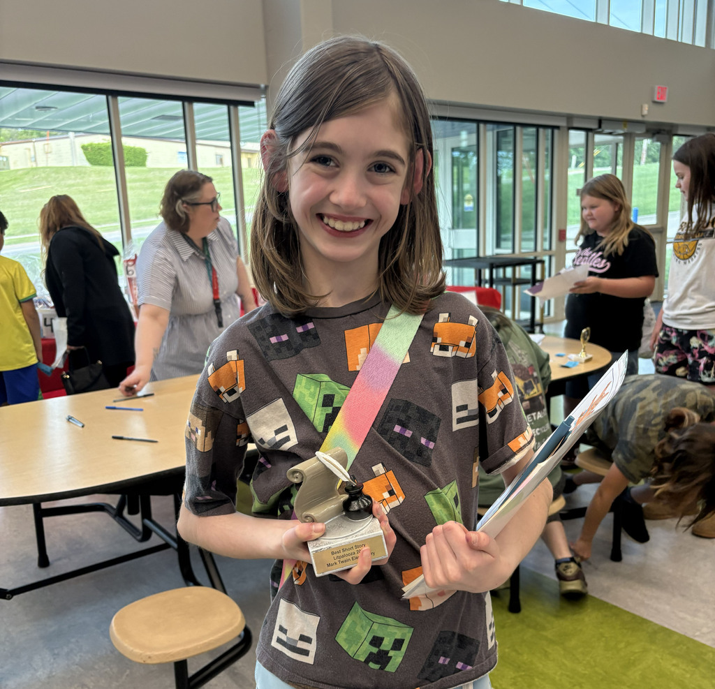 A student in a Minecraft shirt with a writers trophy