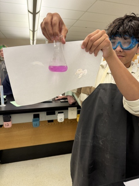 Student with vial of bright pink liquid