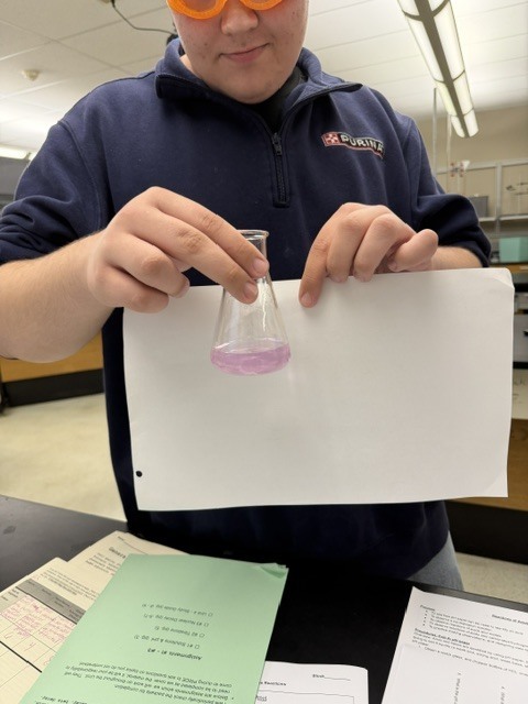Student with vial of light pink liquid