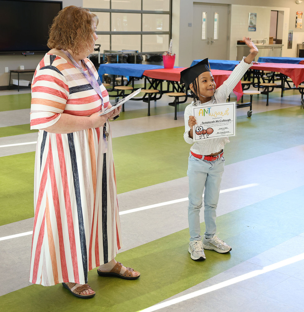 Student waving at his family with Miss Cara