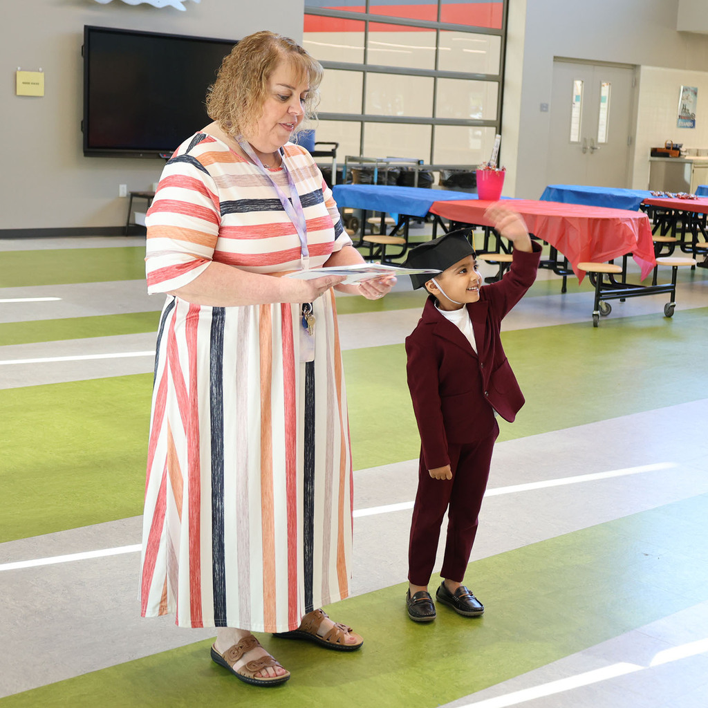 Student waving at his family with Miss Cara