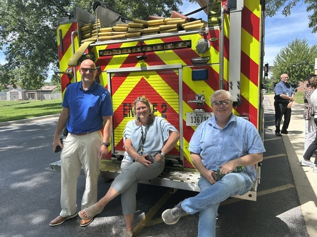Zach Shay, Kristy Cleppe, and Scott Martin on the back of a fire truck