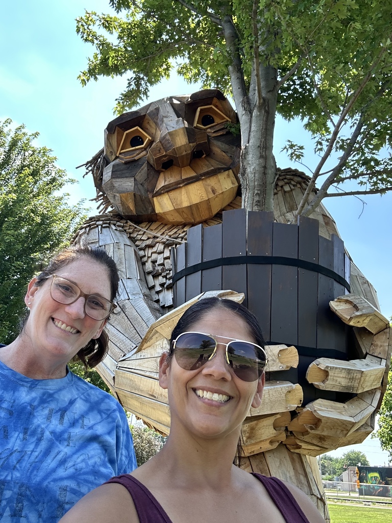 Nicole & Stacey take a selfie with a troll carrying a tree.