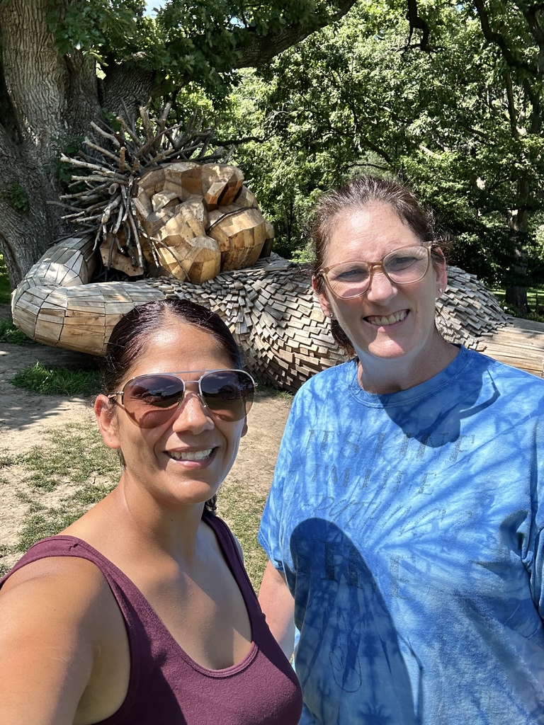 Nicole & Stacey take a selfie with a troll taking a nap by a tree.