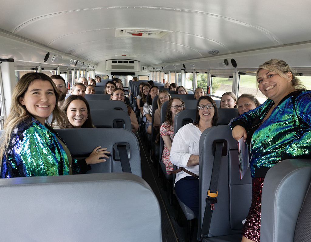 Adriana Cruz and Haleigh Hoyt, tour guides in sequines, with the new teachers on a school bus