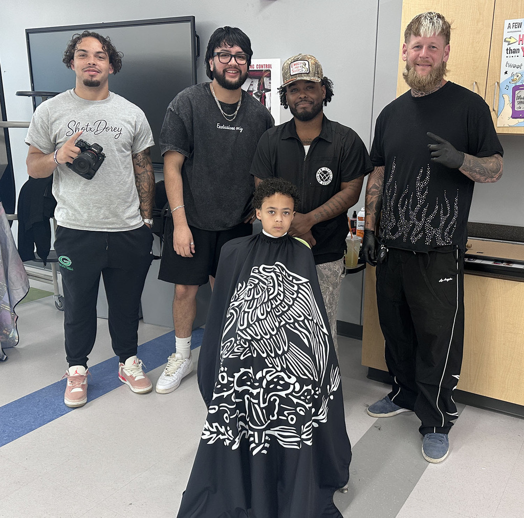 Picture of a young student getting a hair cut with the staff and associates of New Style Barbershop