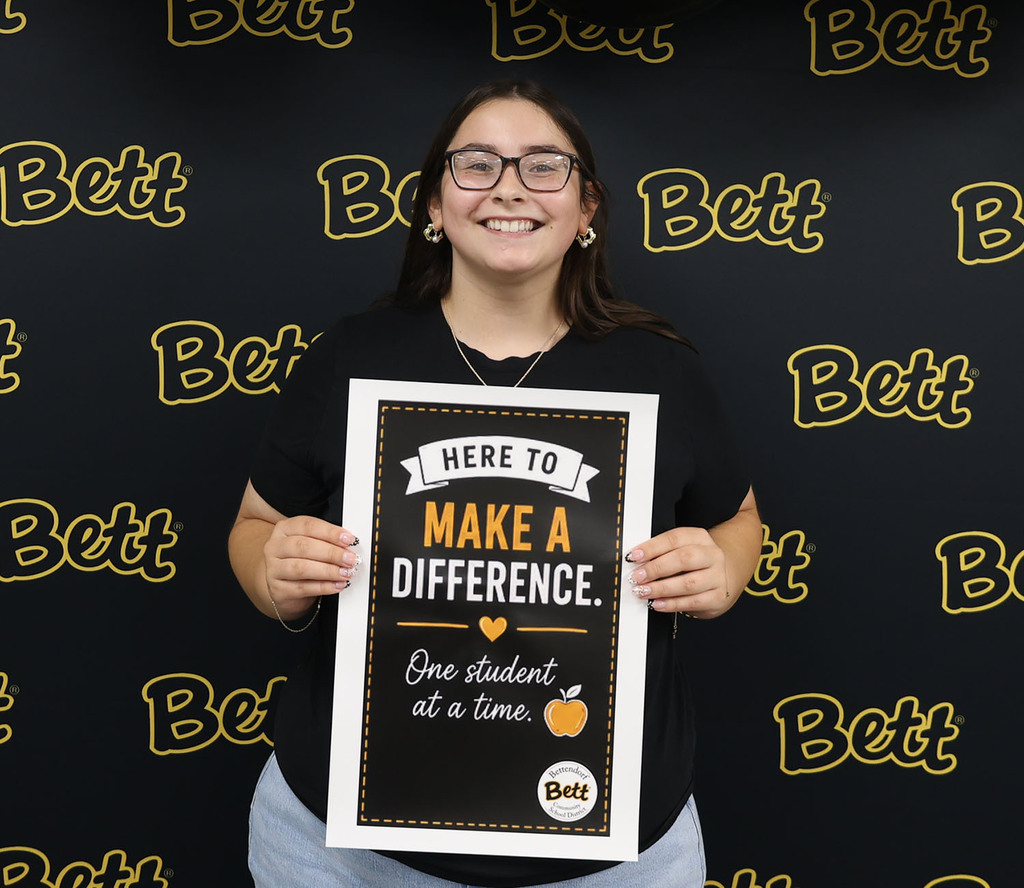 Kasey George with a sign: I'm officially part of the pack! Paw print. Bettendorf Community School District logo with Bett graphic