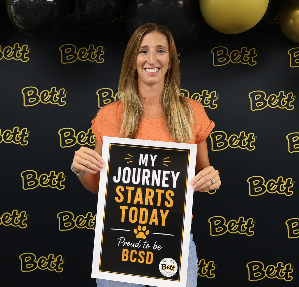 Nicole Dauphin with a sign: My Journey Starts today - paw print - Proud to be BCSD - Bettendorf Commun ity School District logo with Bett graphic