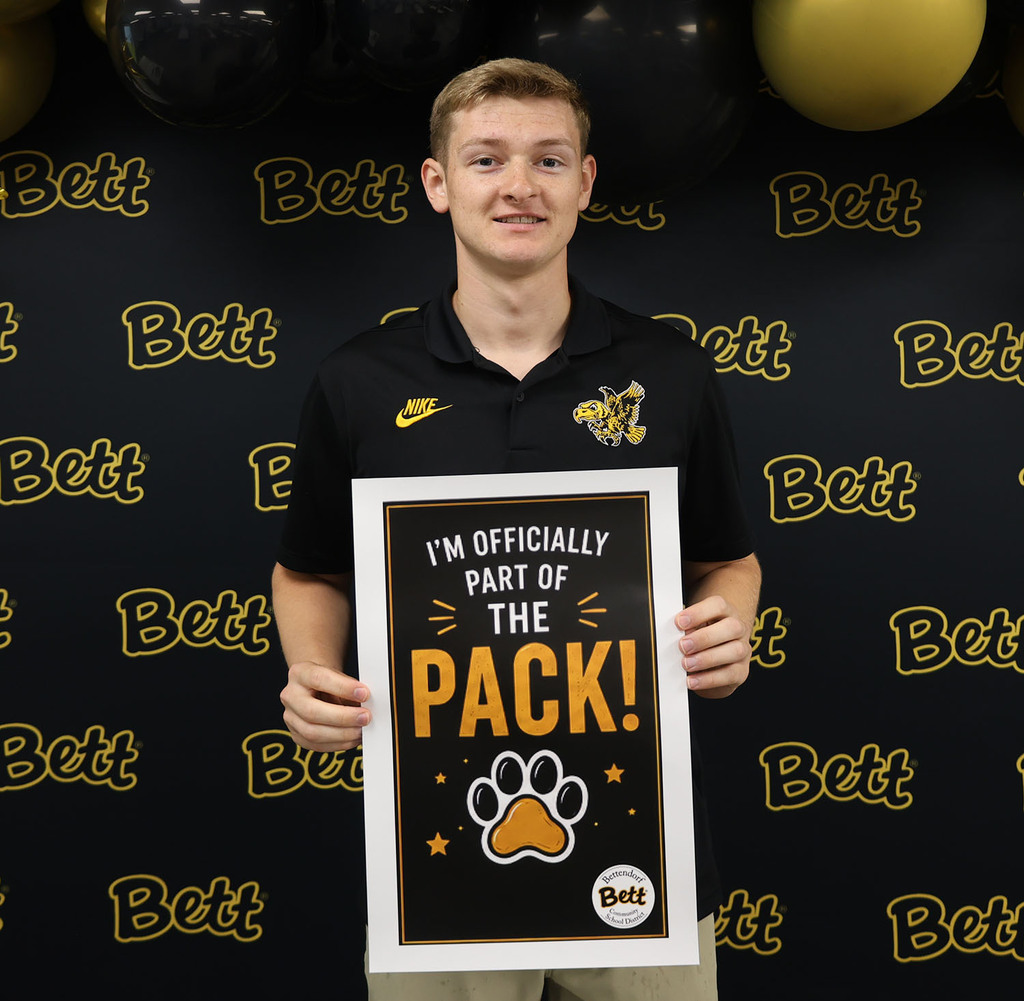 Caleb Pipe with a sign - Kimberly Davis with a sign: I'm officially part of the pack! Paw print. Bettendorf Community School District logo with Bett graphic