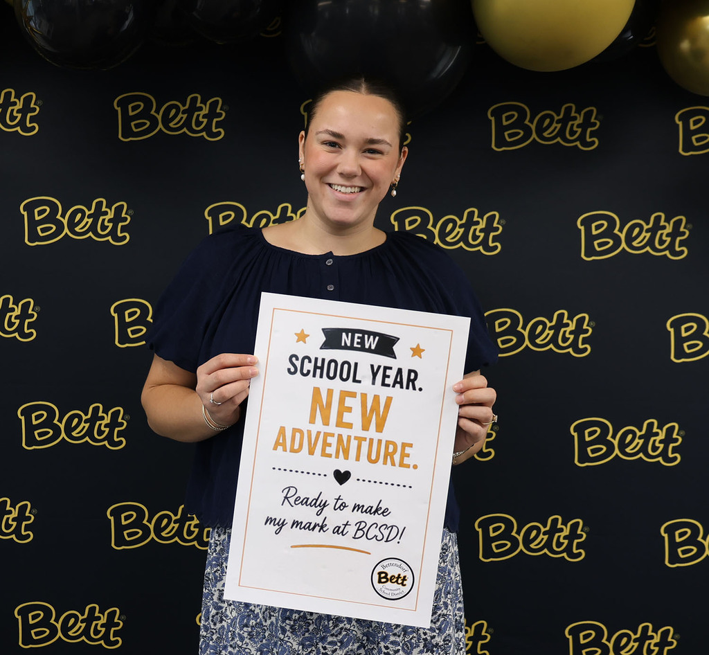Aubrey Weber with a sign: New school year. new adventure. heart. Ready to make my mark at BCSD!  Bettendorf Community School District logo with Bett graphic