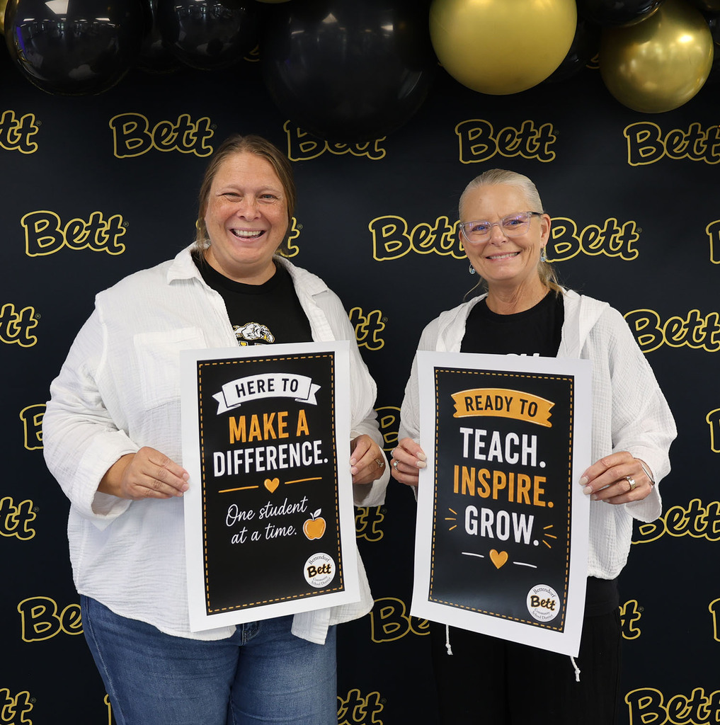 Tracy Lau - BMS Math - - holding a sign: Ready to teach. Inspire. Grow. Heart. Bettendorf Community School District logo with Bett graphic. Michelle Hutton - BHS - holding a sign: Ready to teach. Inspire. Grow. Heart. Bettendorf Community School District logo with Bett graphic.
