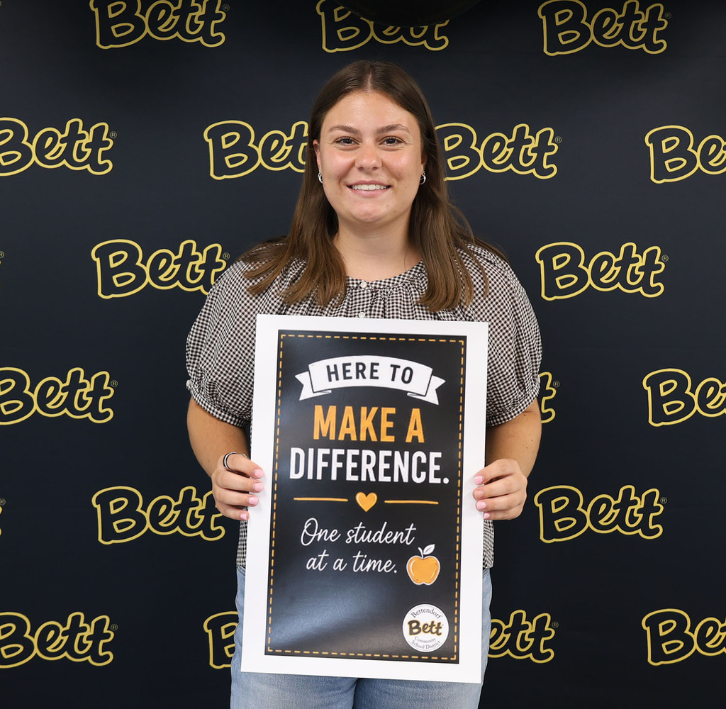 McKenzie Saxton - HH - holding a sign: Here to make a difference. Heart. One student at a time. Apple.  Bettendorf Community School District logo with Bett graphic.