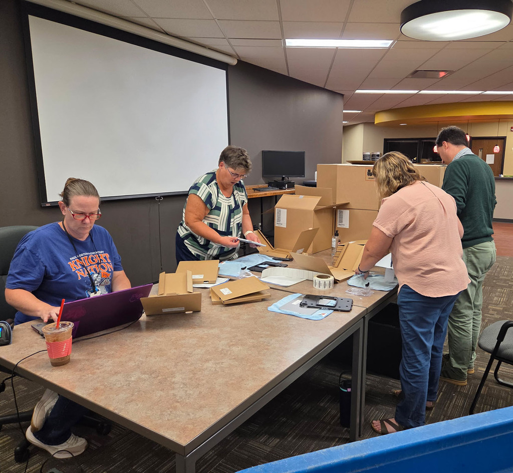 Tech team and admin center staff working on putting covers on student devices