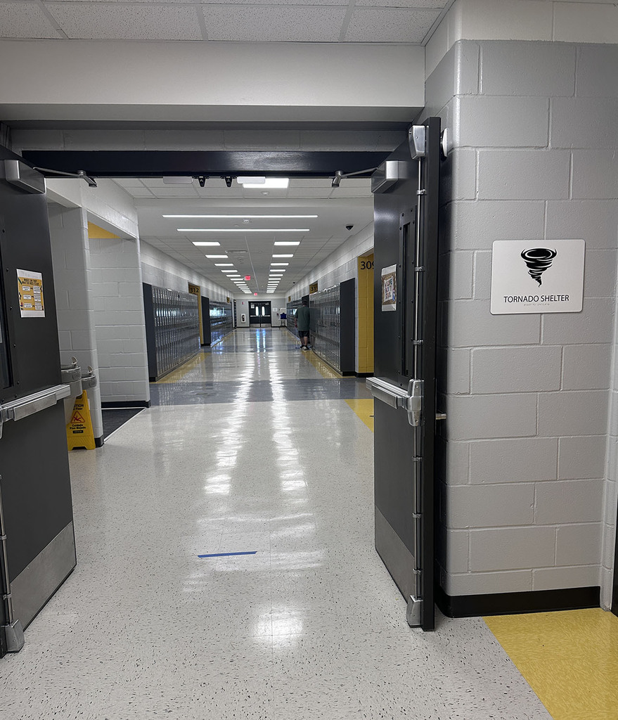 Picture of the new classroom wing through a doorway. Tornado Shelter sign on the wall.