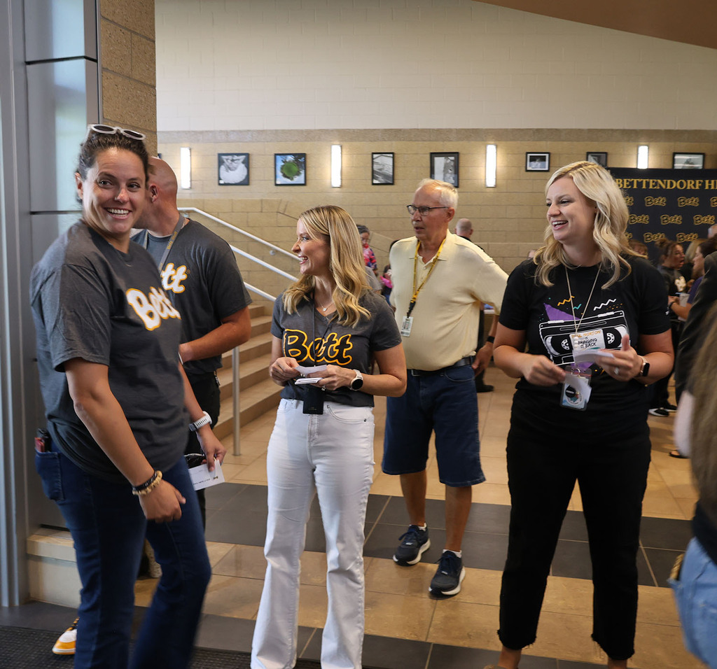 A smiling staff member just entered the front door with administrators handing out raffle tickets behind her