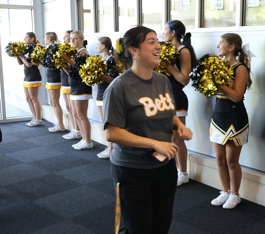 A teacher walking through a corridor of cheerleaders in the vestibule